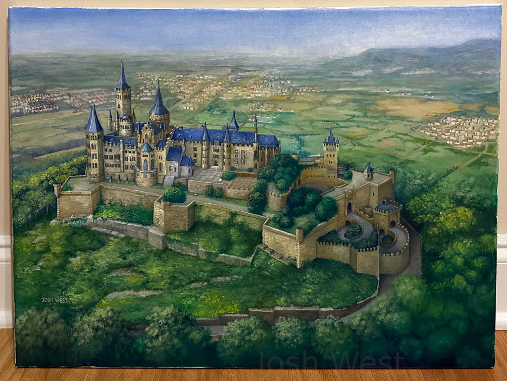 An aerial view of Hohenzollern Castle in Germany, a large sprawling castle set atop a hill and surrounded by forest, with villages seen in the distance behind it